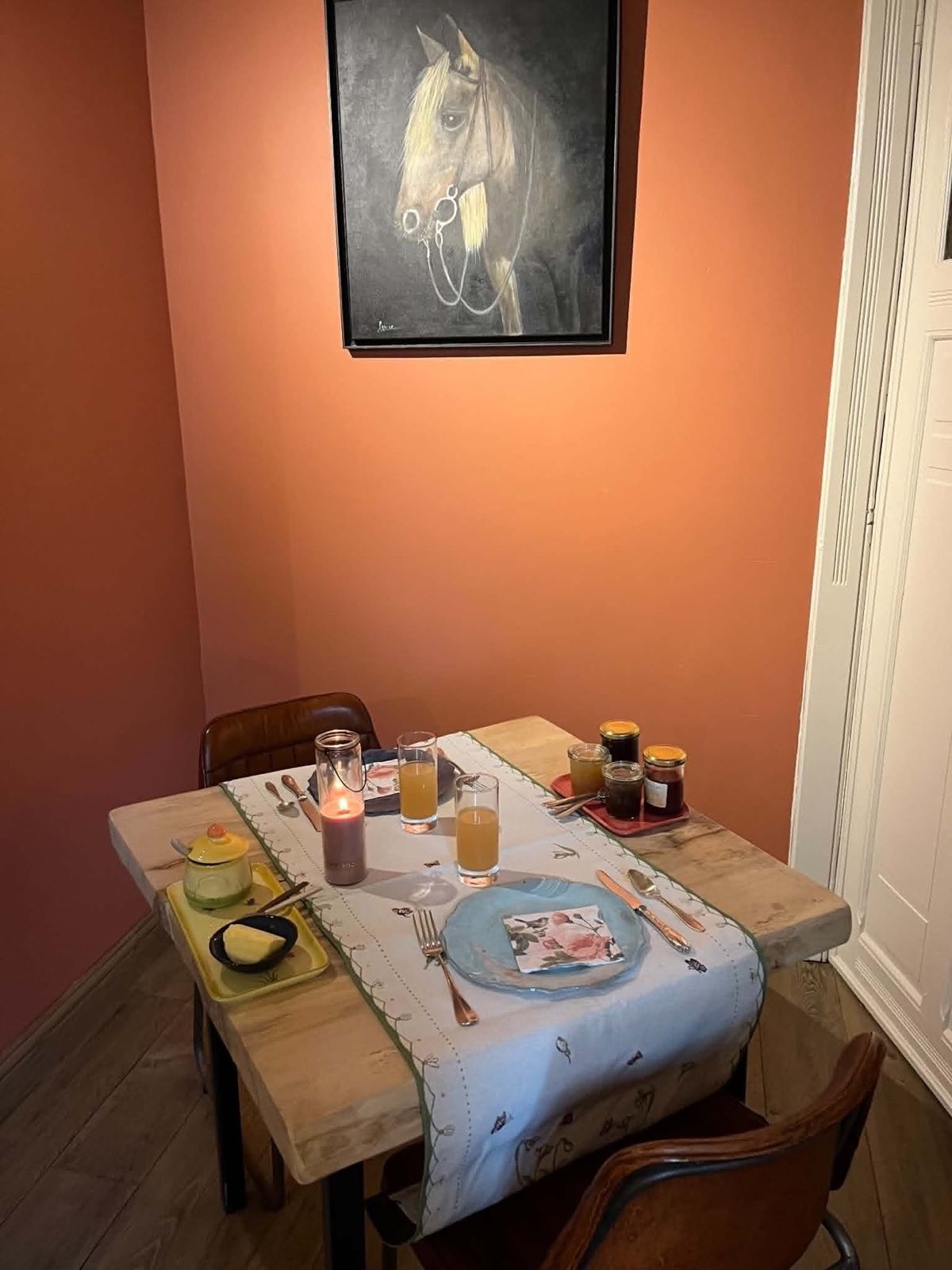 La table du petit-déjeuner dressée dans le petit salon de La Roseraie, sous une toile de cheval