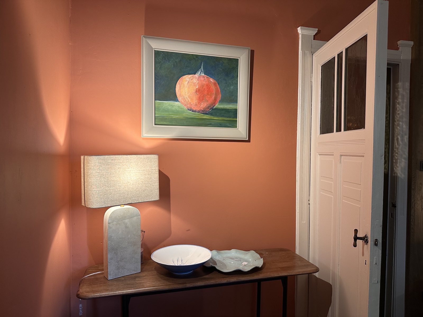 Un coin du petit salon de La Roseraie : une toile de potiron, une lampe, et deux céramiques posées sur une console